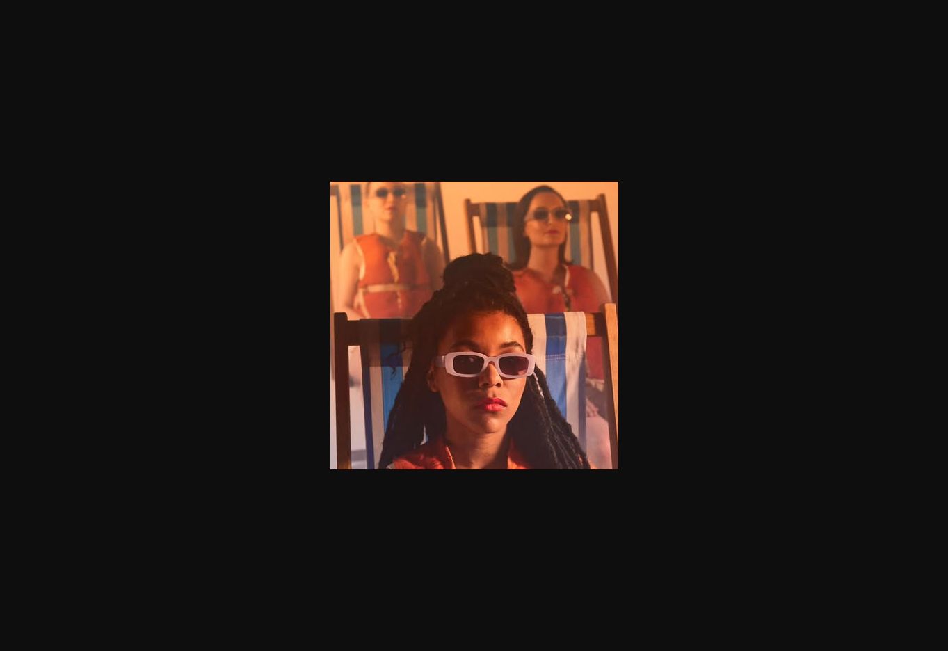 A performer in sunglasses lit by warm orange stage light